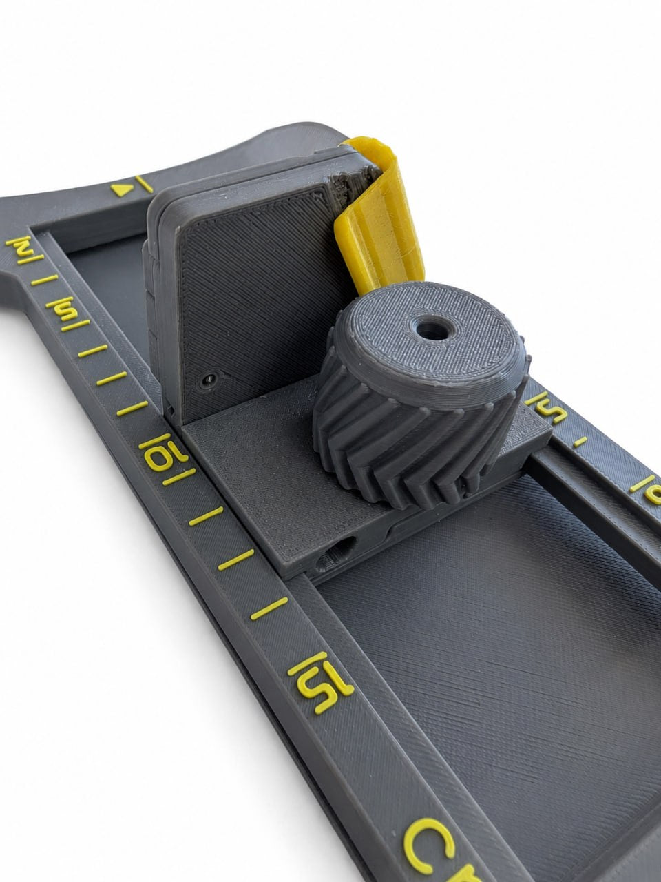 Close-up of 3D printed hat brim cutter showing the adjustable guide, textured control knob, angled blade holder, and measuring scale