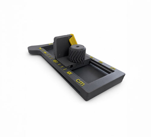Angled side view of 3D printed hat brim cutter with adjustable guide, cutting blade, and centimeter and inch measuring scales