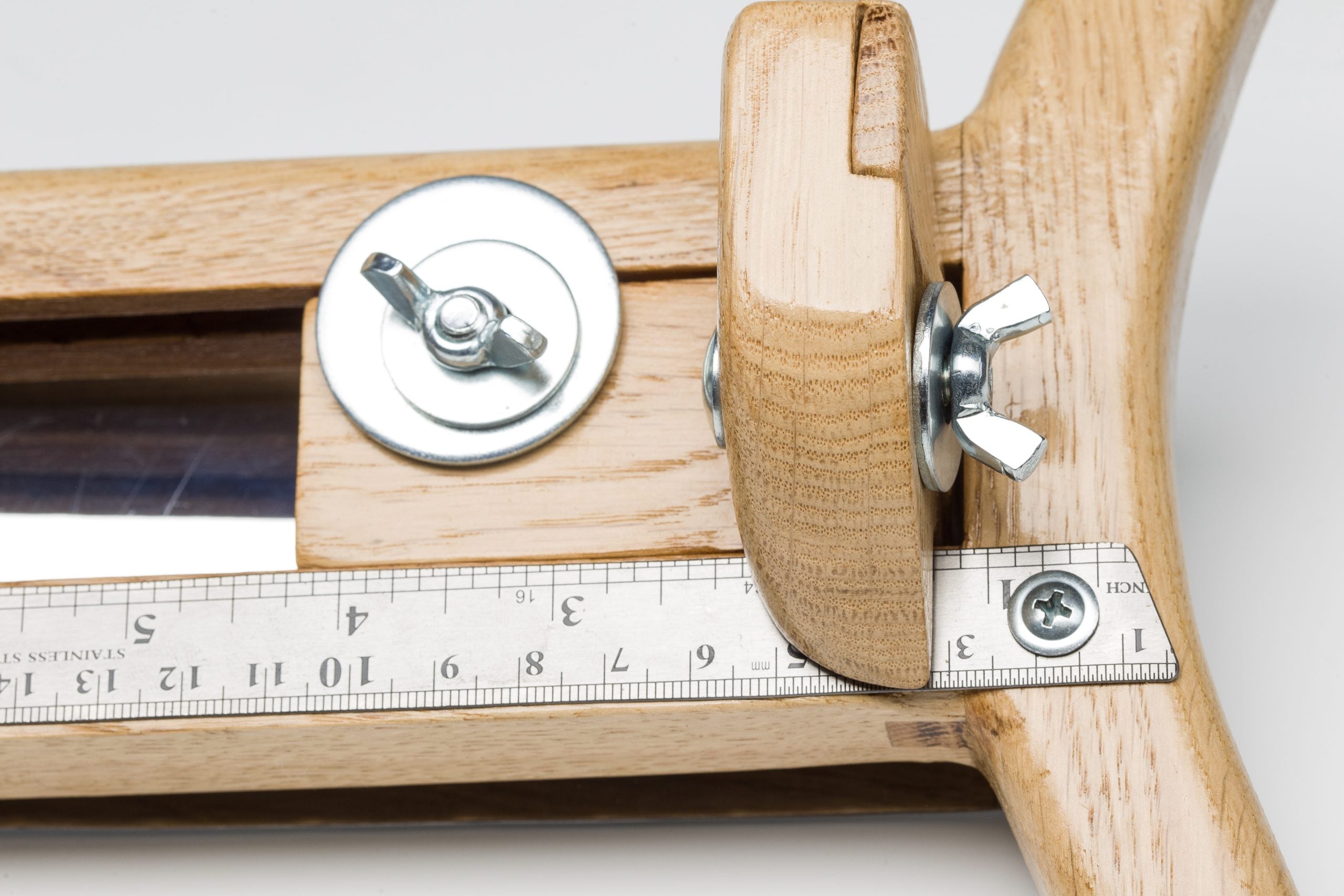 Close-up of wooden hat brim cutter with adjustable stop and metal ruler for precise felt brim measurement