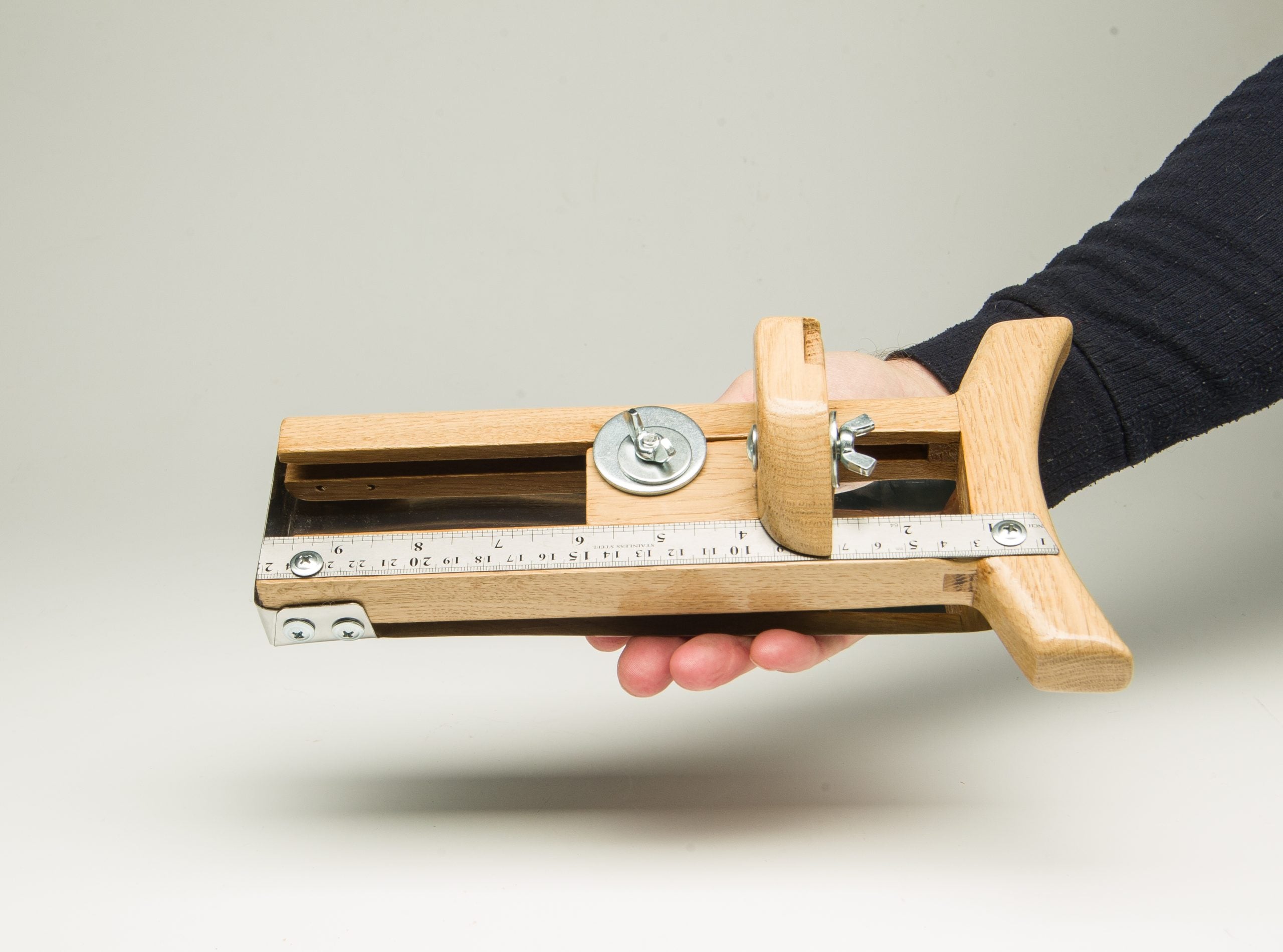 Wooden hat brim cutter tool held in hand for shaping felt hats