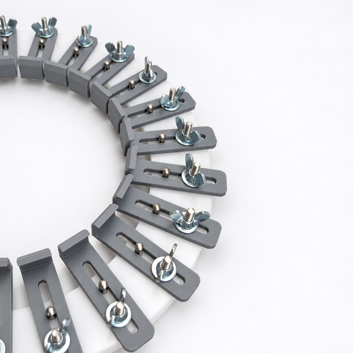 Angled close-up of gray adjustable fingers secured with metal washers and wing nuts on a white acrylic hat conformateur used to record individual head contours.